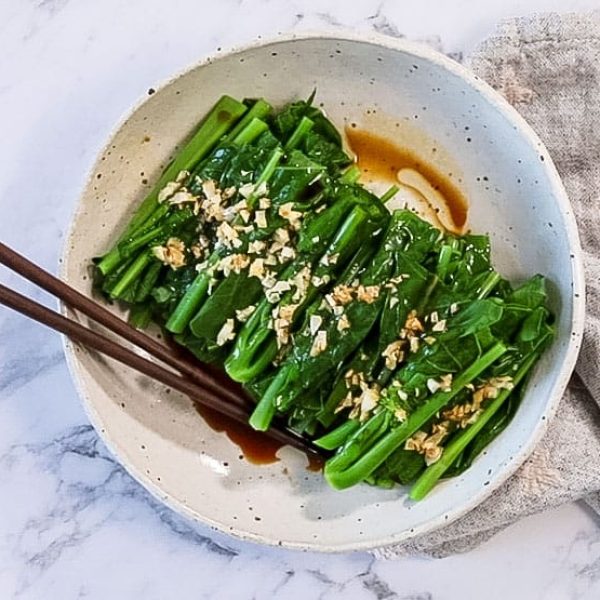 landscape view of chinese steamed vegetables on a plate with a pair of chopstick