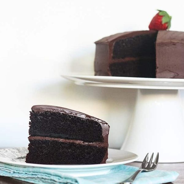 a piece of steam oven chocolate cake in front of the cake on a white stand