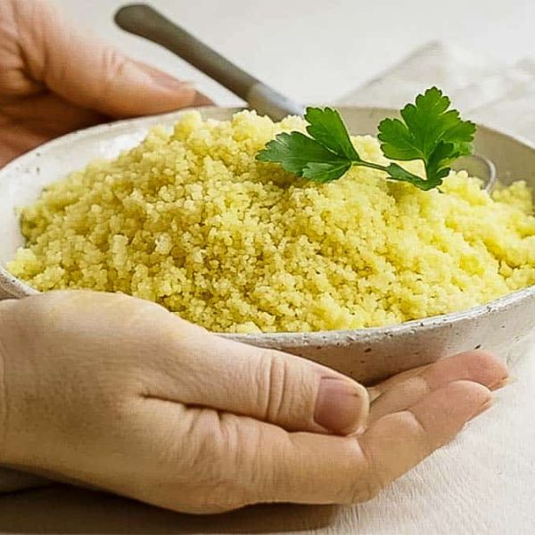 bowl of couscous being presented by two hands