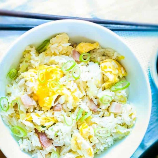Steam oven egg fried rice in a white bowl, with a small ramekin of sauce and chopsticks on the placemat beside it.