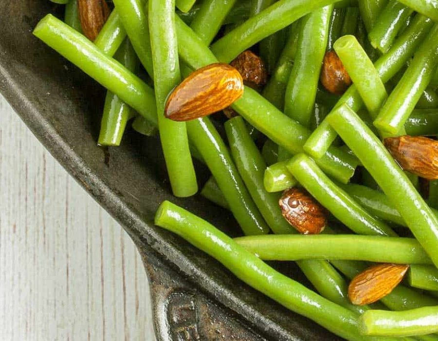 vibrant, glossy green beans and almonds in a steel baking dish
