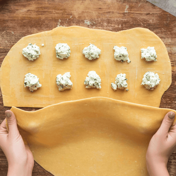 sheet of pasta with cheese balls for making homemade ravioli