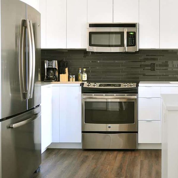 A kitchen with white benches and a large steam oven and range with a microwave above it