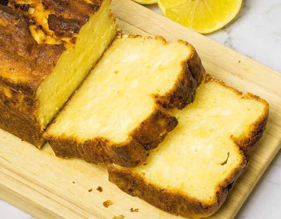 lemon ricotta steam oven cake, resting on a wooden board with two slices cut from the end of the loaf