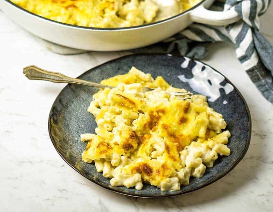 a dark blue plate with a serving of macaroni and cheese, and fork to the side
