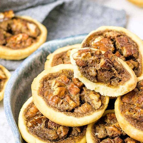 mini pecan pies in a blue pottery dish with some on a napkin in the background