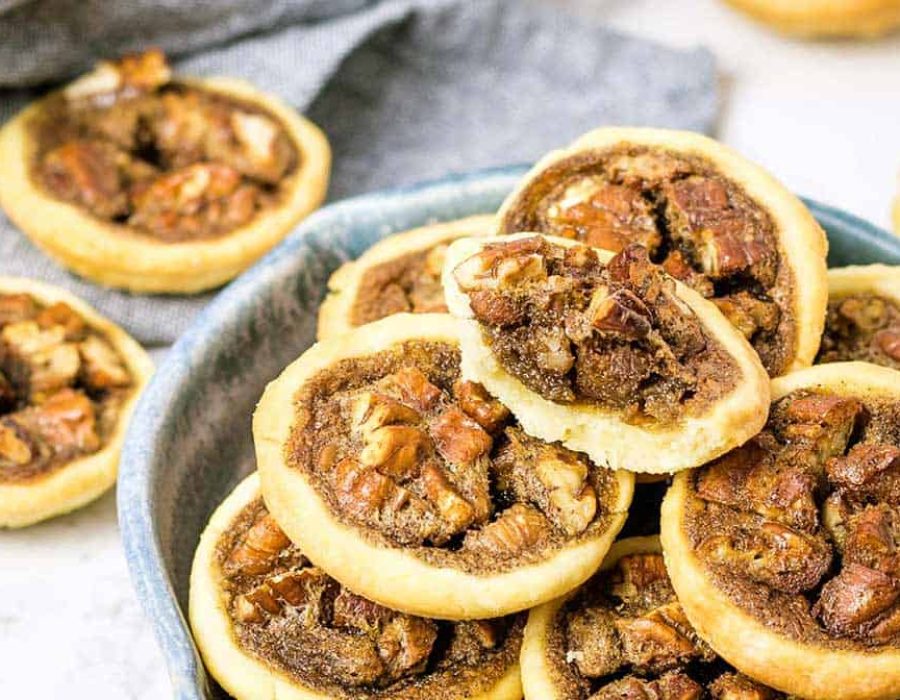 mini pecan pies in a blue pottery dish with some on a napkin in the background