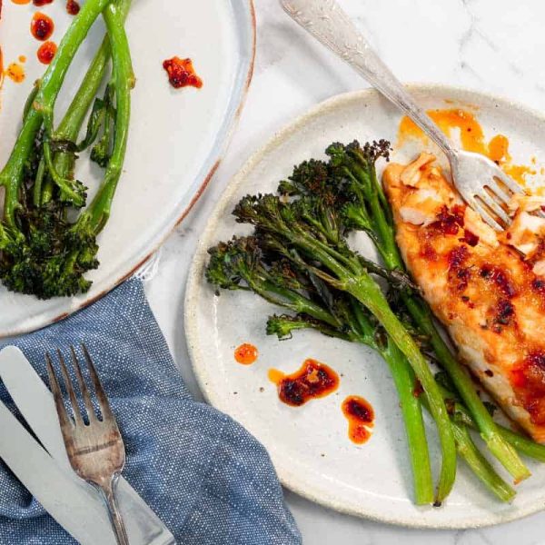 Miso-Roasted-Salmon-process-7 Two plates of roasted salmon with broccolini, topped with chili oil.