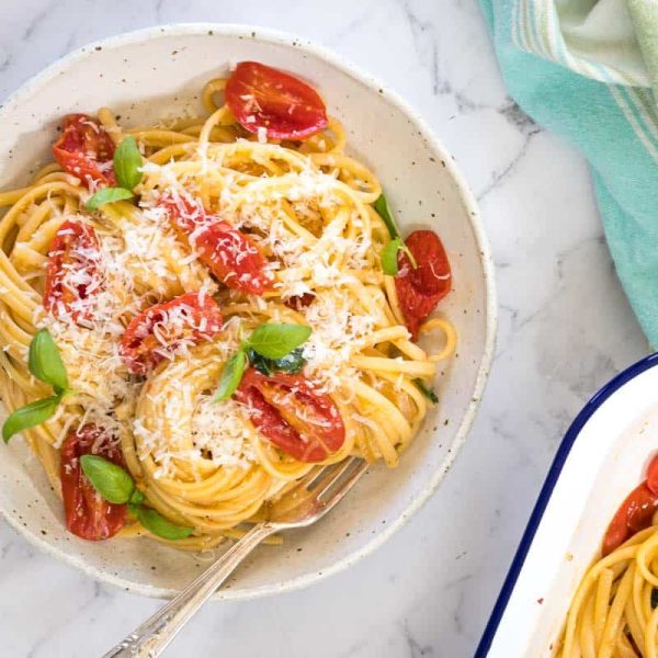 Top-down view of a ceramic bowl filled with steam oven pasta sits next to a green and white kitchen towel.