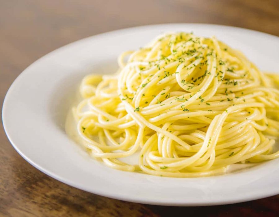 Cooked Italian spaghetti seasoning with ground parsley on white plate