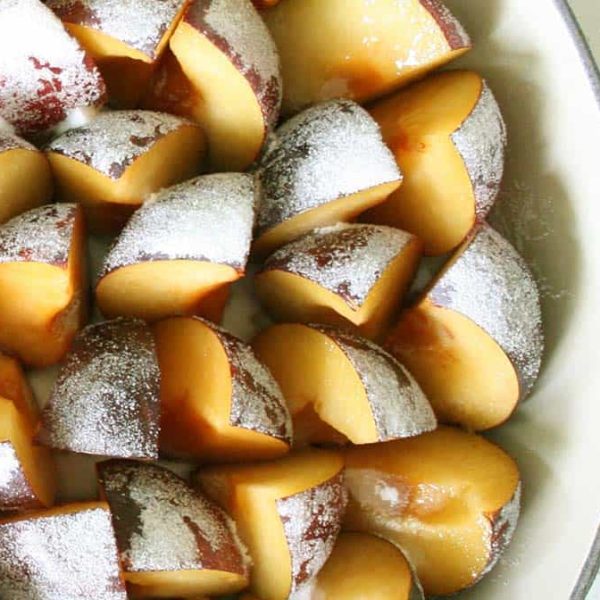 Roasted Plums 1080×675 Web a white baking dish filled with sliced plums arranged standing up dusted with sugar