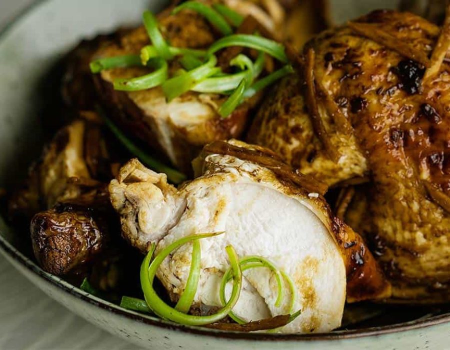 A close up picture of succulent soy sauce chicken in a grey bowl