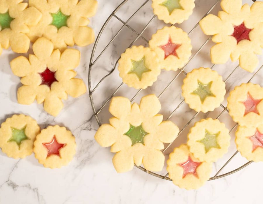 Landscape view of stained glass cookies on a cooling rack and marble countertop.