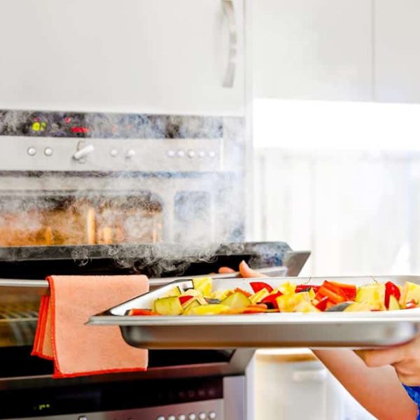 woman putting vegetables into steam oven