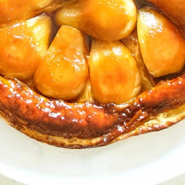 a close up image of golden apple pieces in a puff pastry shell on a white plate