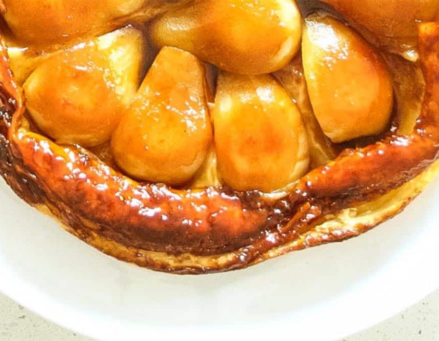 a close up image of golden apple pieces in a puff pastry shell on a white plate